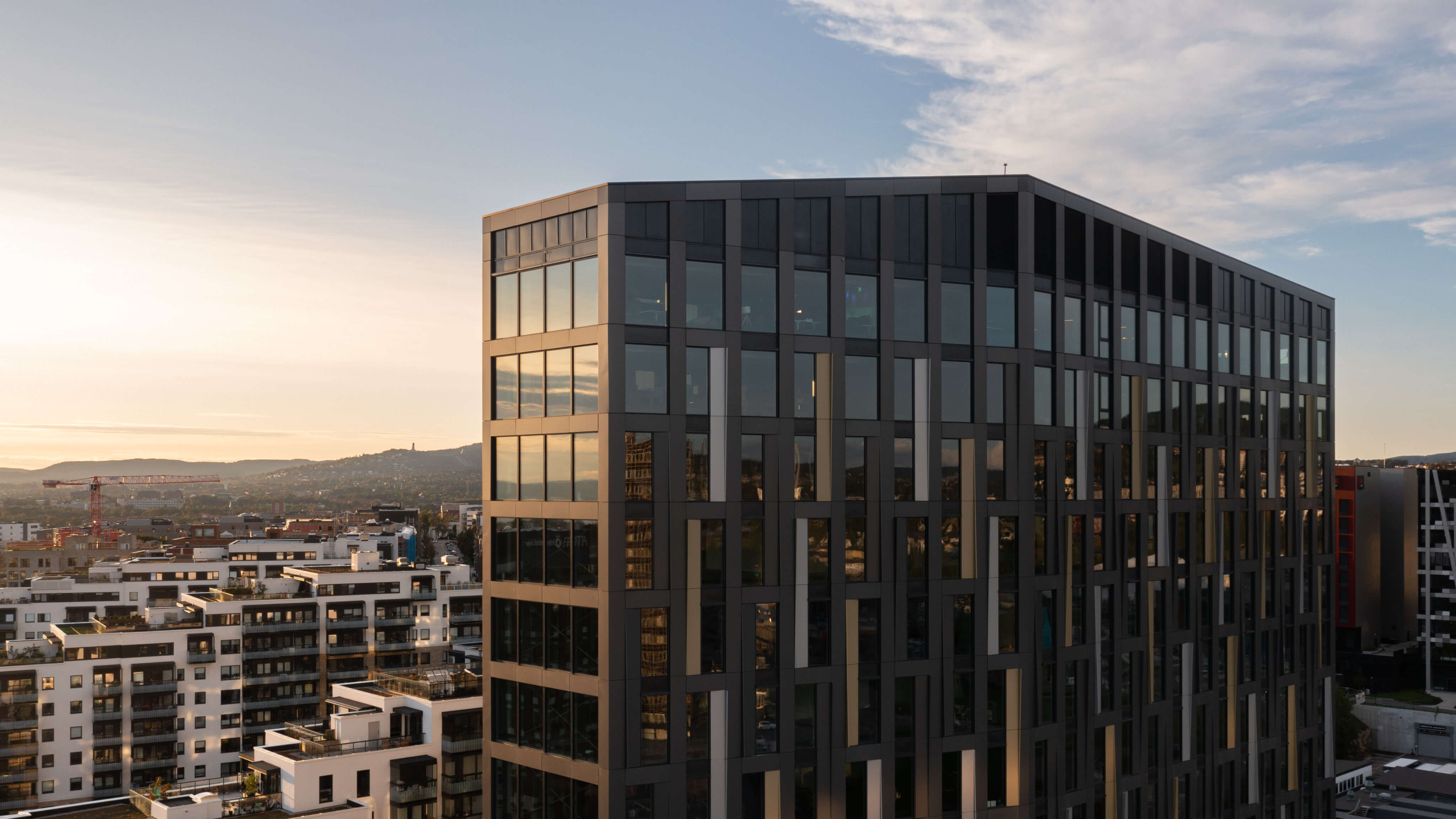 Bilde av Parallell-bygningen, et moderne kontorbygg med en distinkt, stilig arkitektur og glatte glassfasader som reflekterer det urbane landskapet rundt.